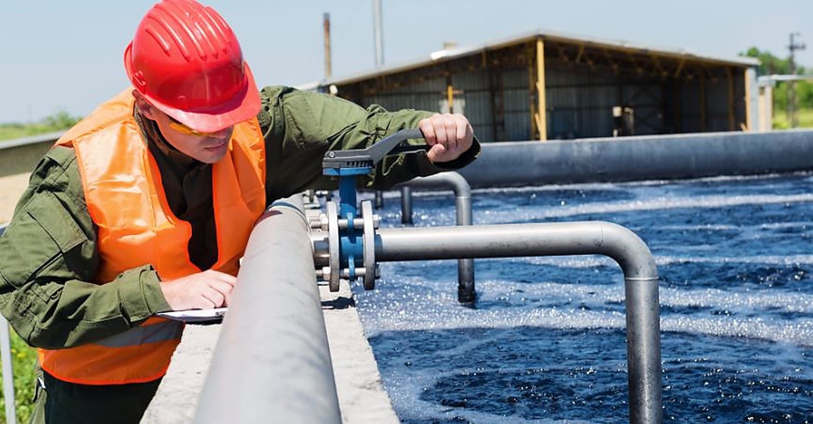 Maintenance technician in safety gear inspecting a water treatment basin during a scheduled service visit