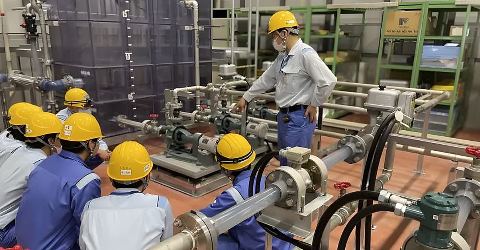 Engineers in safety helmets reviewing pump and pipework upgrades at a treatment plant