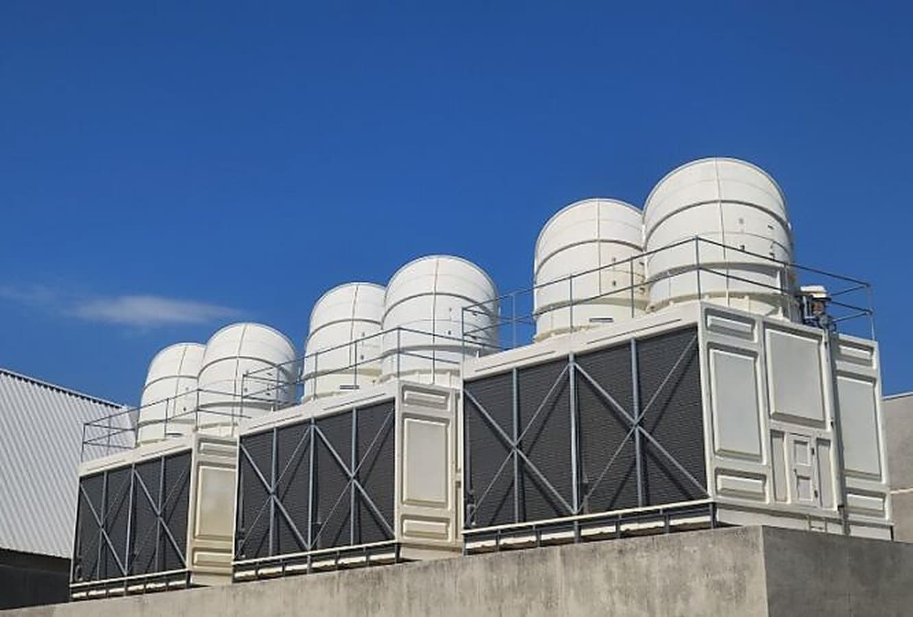 Rooftop cooling tower bank protected by chemical-free water conditioning against scale